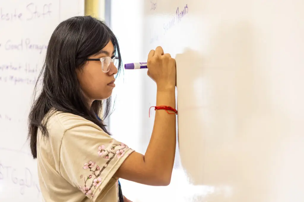 Omaha high school student at a whiteboard.